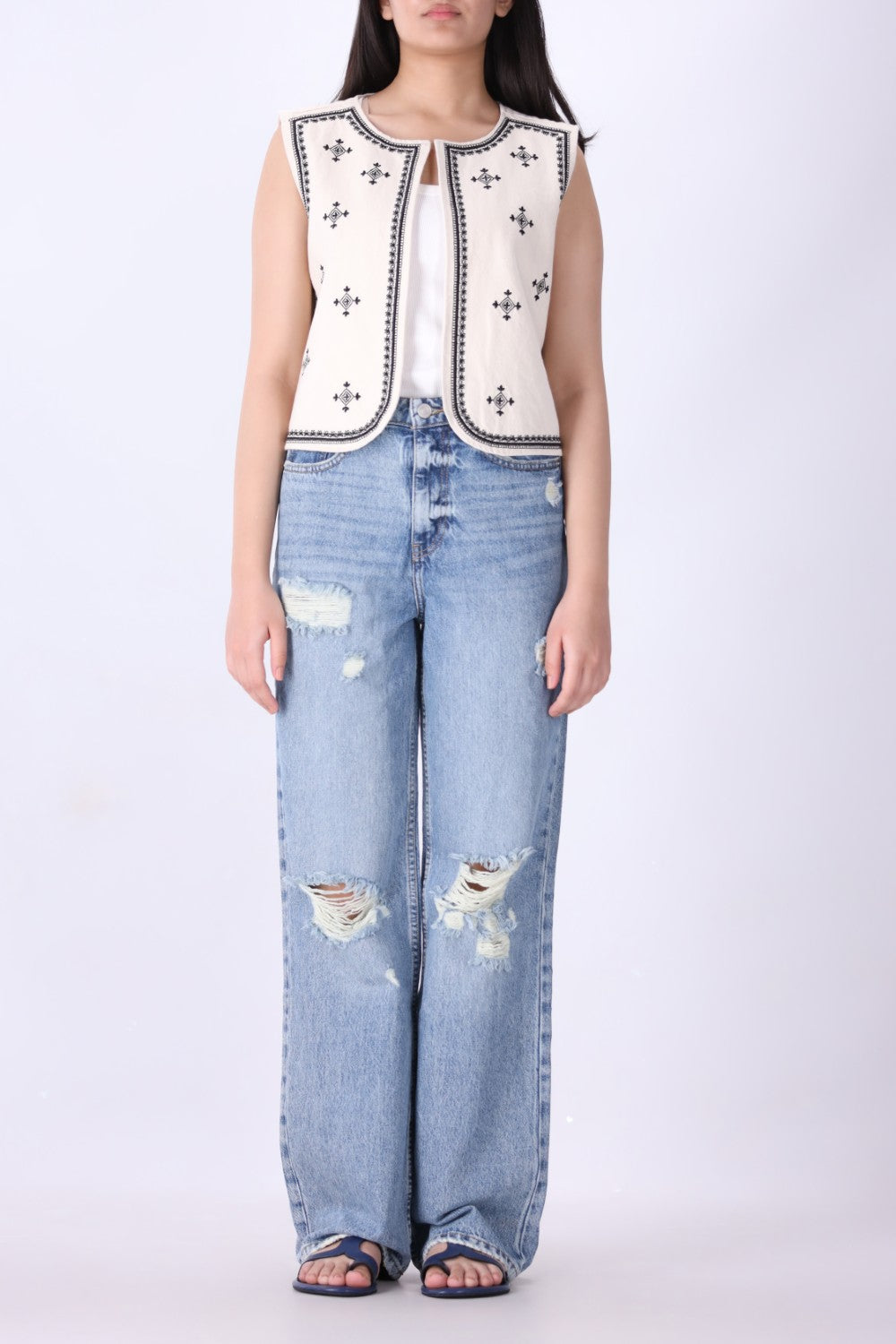 Close-up of geometric embroidery detail on ivory vest