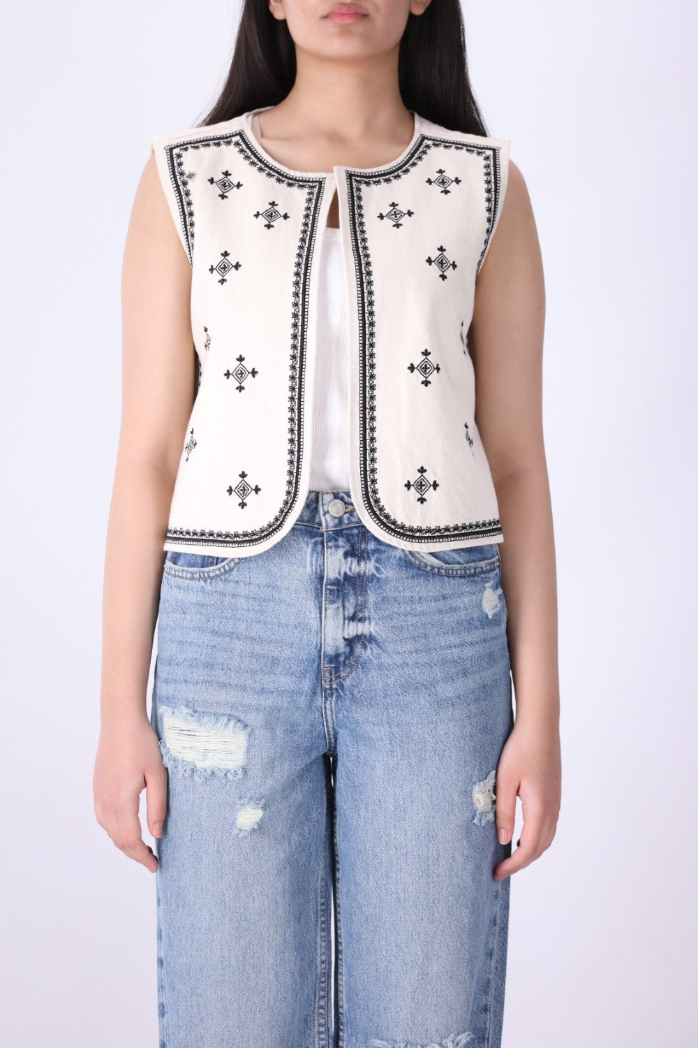 Embroidered vest layered over a plain tee and denim
